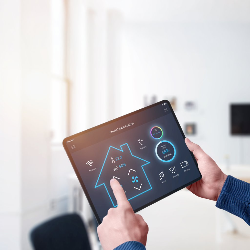 Hands holding a tablet showing a smart home control app with temperature, humidity and lighting controls